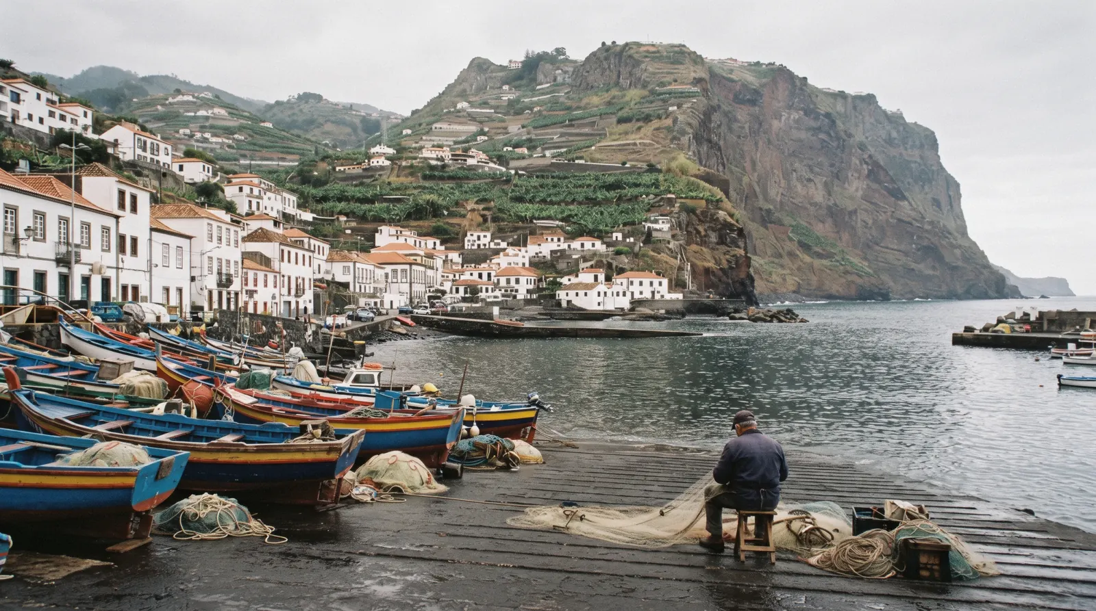 Striped fishing boats on the slipway of Câmara de Lobos with the Cabo Girão cliff behind, a half day from Funchal, Portugal
