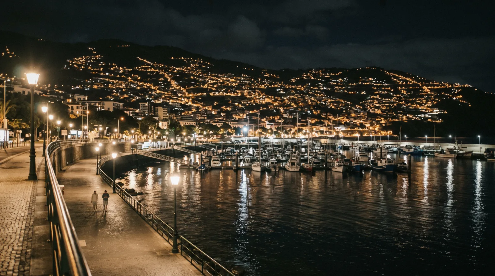Funchal's illuminated seafront and marina after dark with city lights reflecting on the water in Madeira
