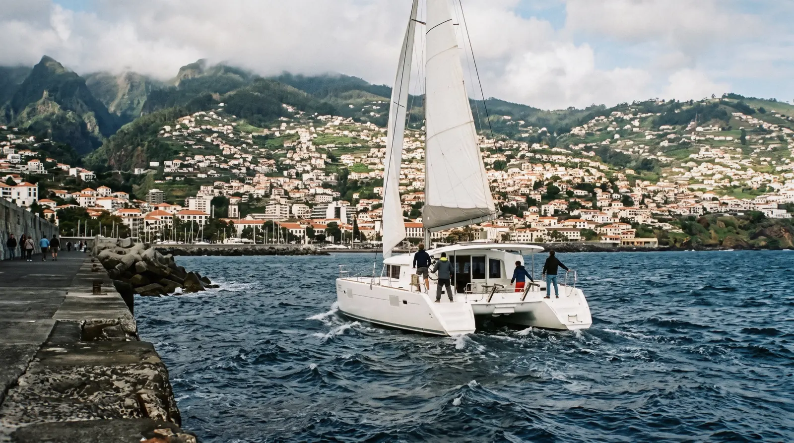 A catamaran leaving the marina with the city climbing the mountainside behind it in Funchal, Portugal