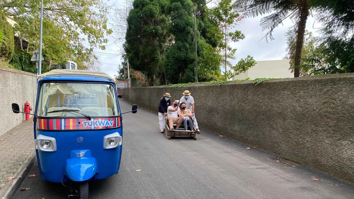 A wicker toboggan basket steered down a paved street from Monte on a Monte Tropical Garden and toboggan ride by tuk tuk in Monte, Madeira