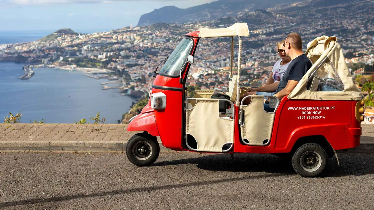 A tuk-tuk parked at Miradouro do Pináculo overlooking Funchal Bay on a tuk tuk tour to the most breathtaking viewpoints in Funchal, Portugal