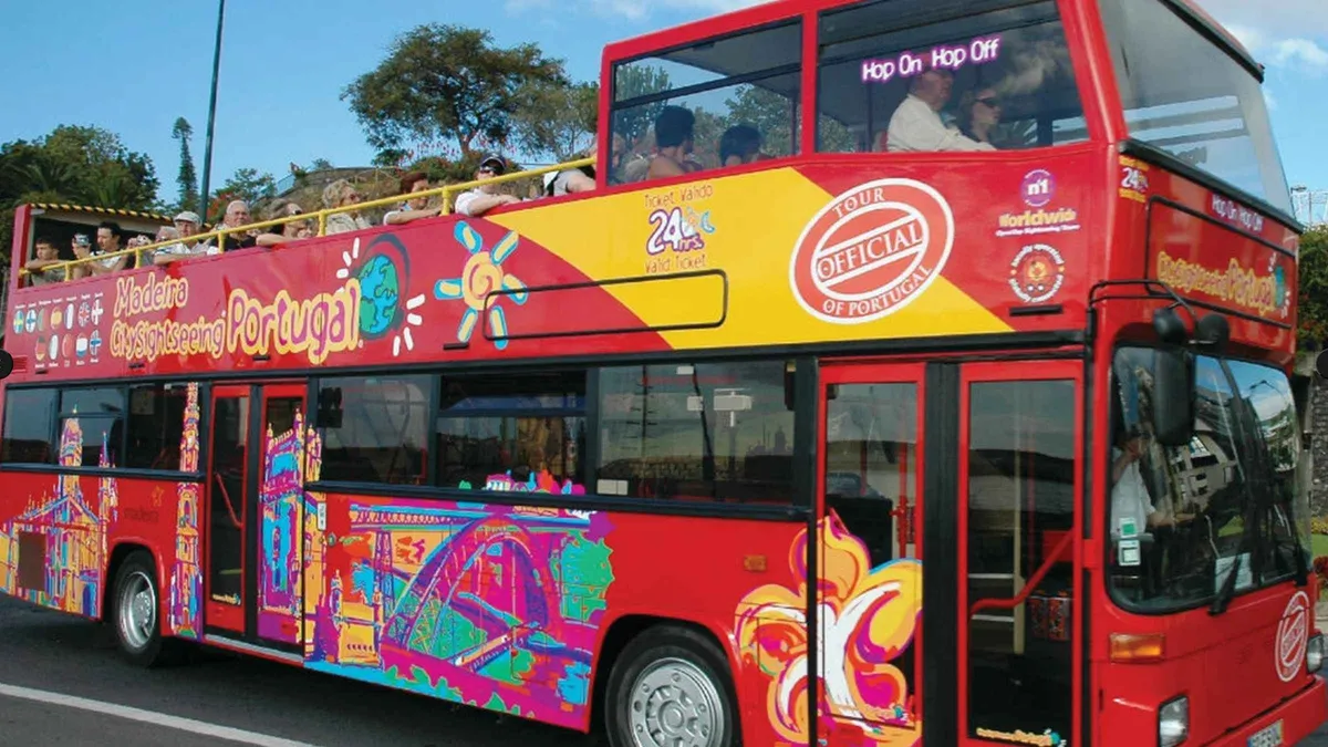 An open-top double-decker sightseeing bus parked along Funchal's seafront on a City Sightseeing hop-on hop-off bus tour in Funchal, Portugal