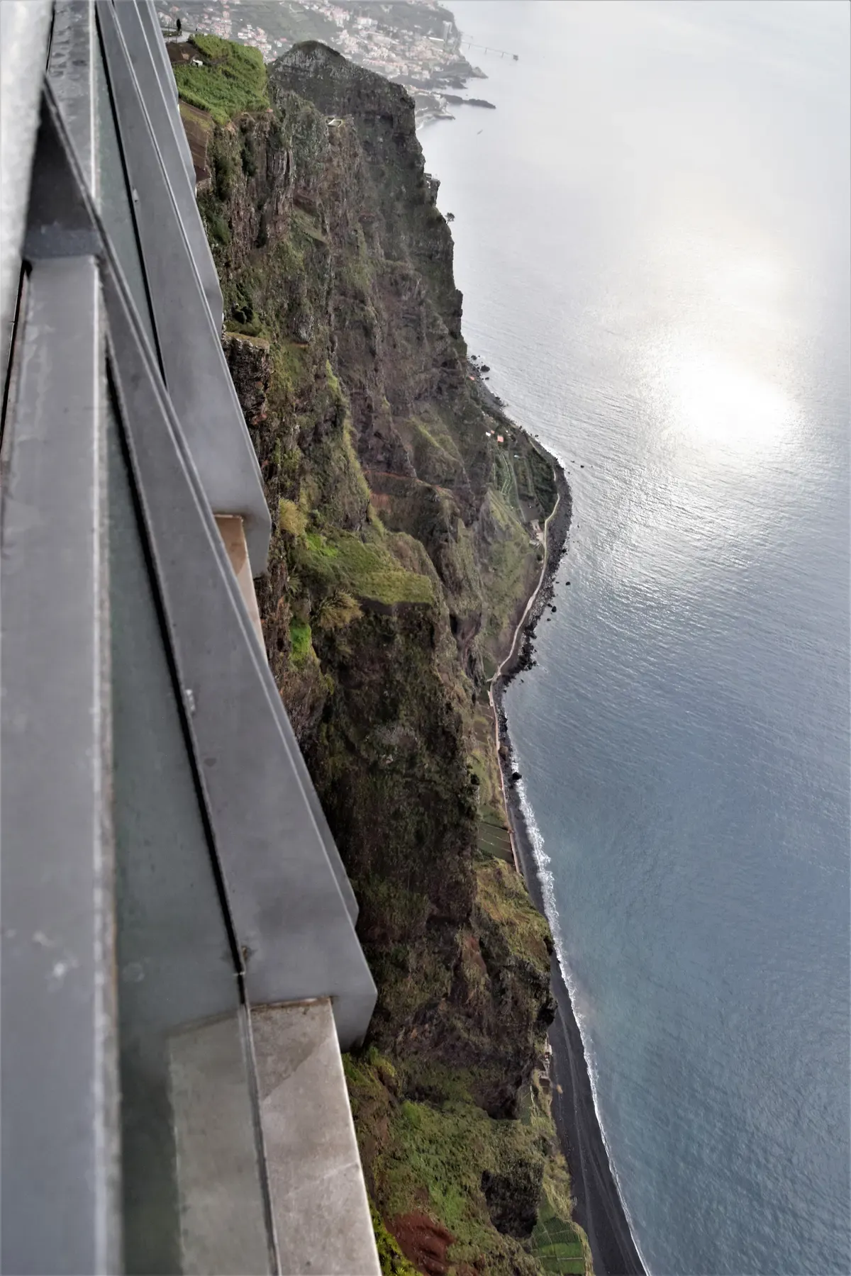 A visitor standing on the glass skywalk platform at Cabo Girao above the cliffs near Funchal, Madeira