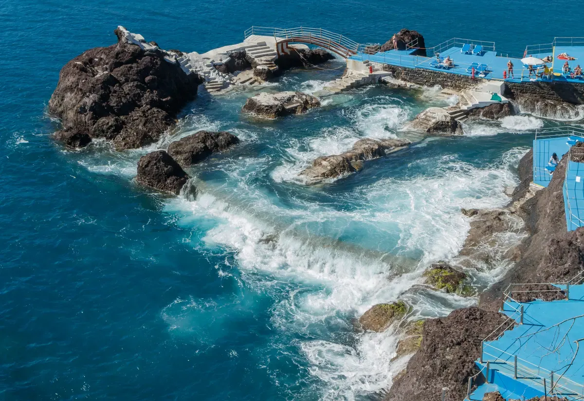 Waves breaking over volcanic rock pools at the Doca do Cavacas bathing complex in Funchal, Madeira