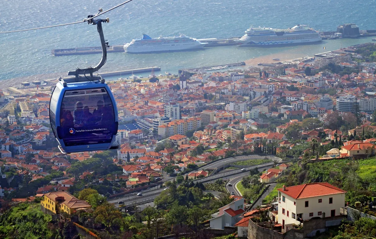 A Funchal cable car cabin descending towards the city with two cruise ships docked in the harbour below, Funchal, Madeira