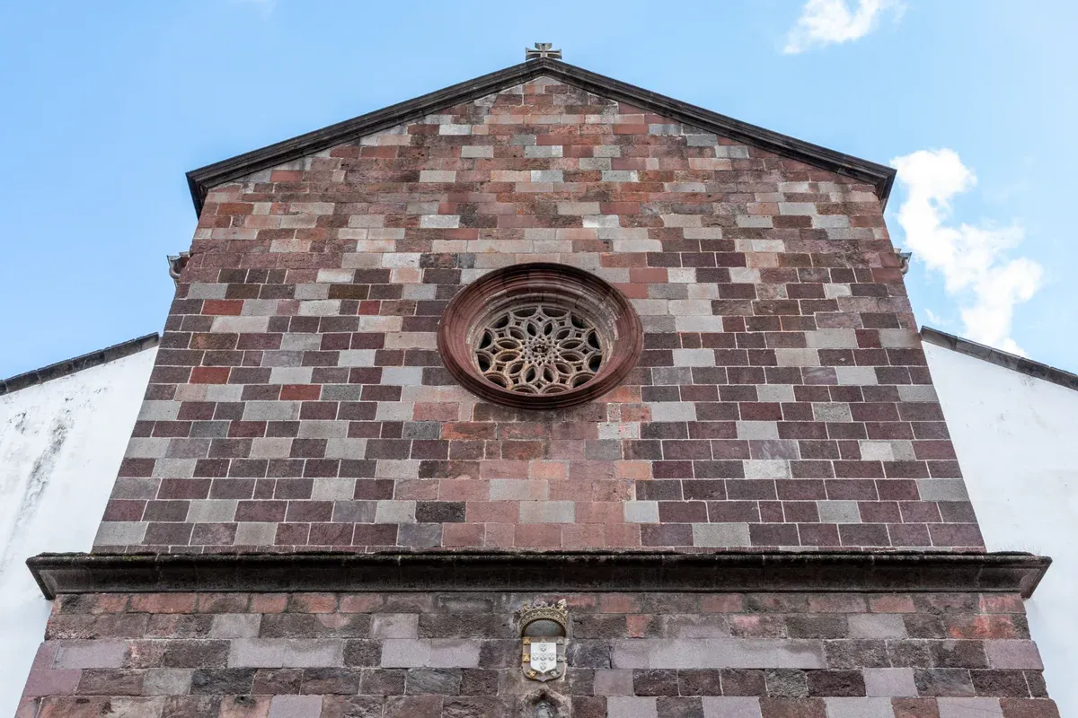 The rose window and volcanic stone gable of the Se do Funchal cathedral facade in Funchal, Madeira, Portugal