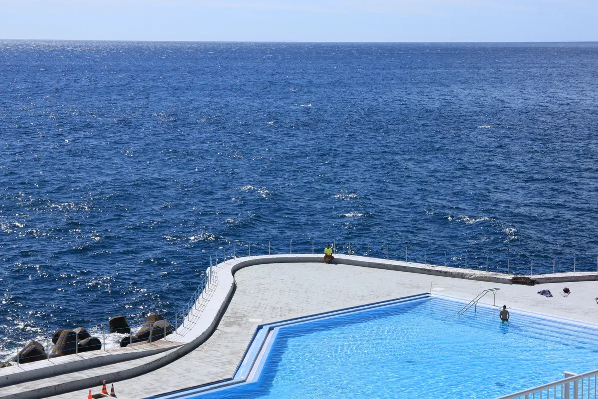 The Lido seawater pool built out over the Atlantic in Funchal, Madeira, with a swimmer and the open sea beyond the pool wall