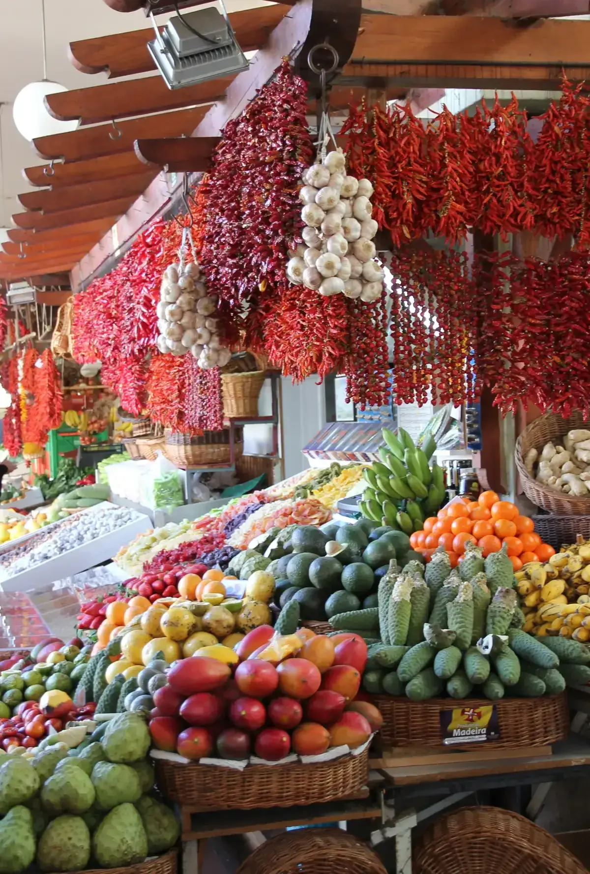 Dried chillies, garlic and fresh produce hanging at a market stall in the Mercado dos Lavradores in Funchal, Portugal